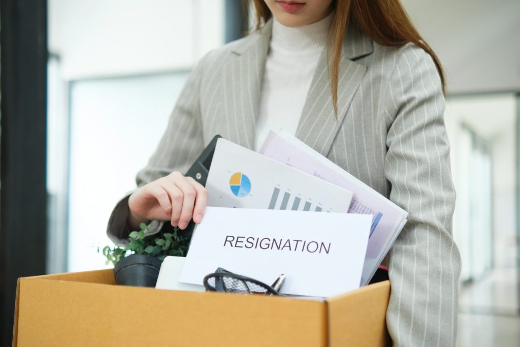 A businesswoman packing personal belongings, deciding on resignation, changing jobs, or being fired.